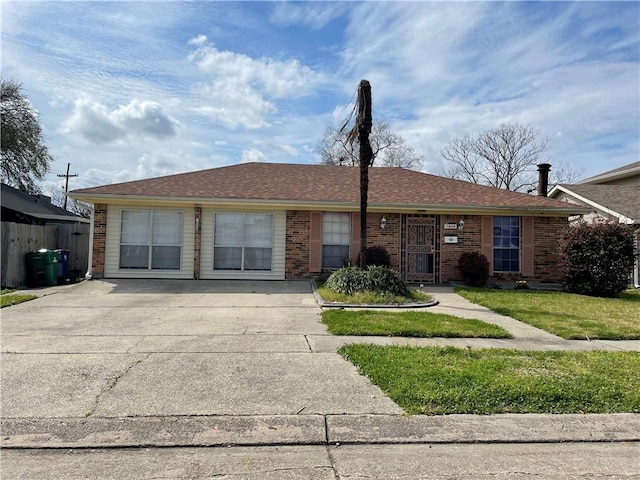 single story home featuring brick siding, a shingled roof, a front yard, and fence