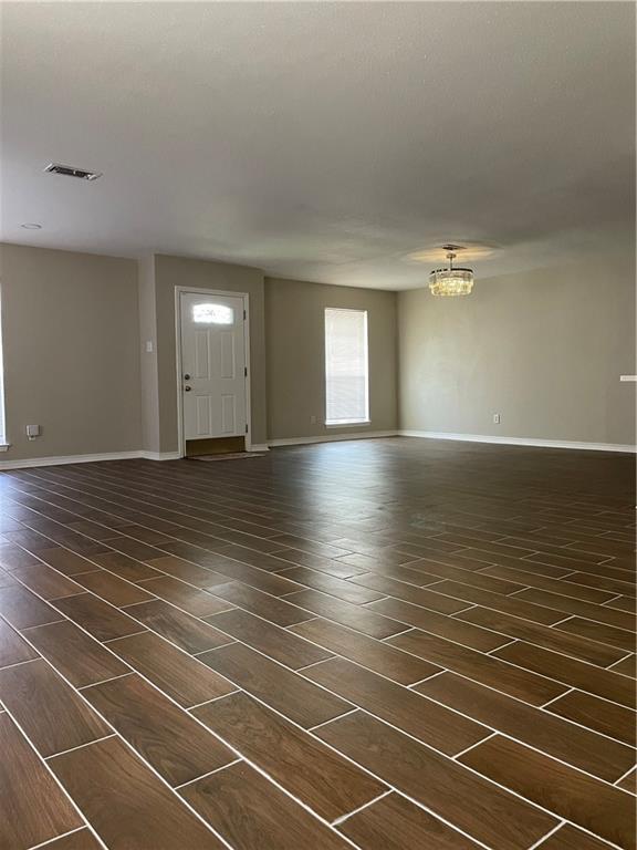 interior space with dark wood finished floors, visible vents, a chandelier, and baseboards