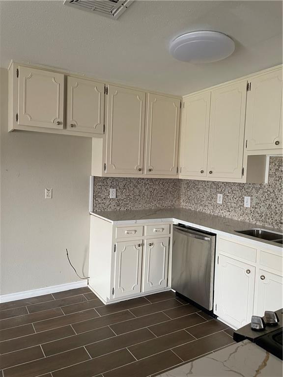 kitchen with decorative backsplash, wood finish floors, and stainless steel dishwasher