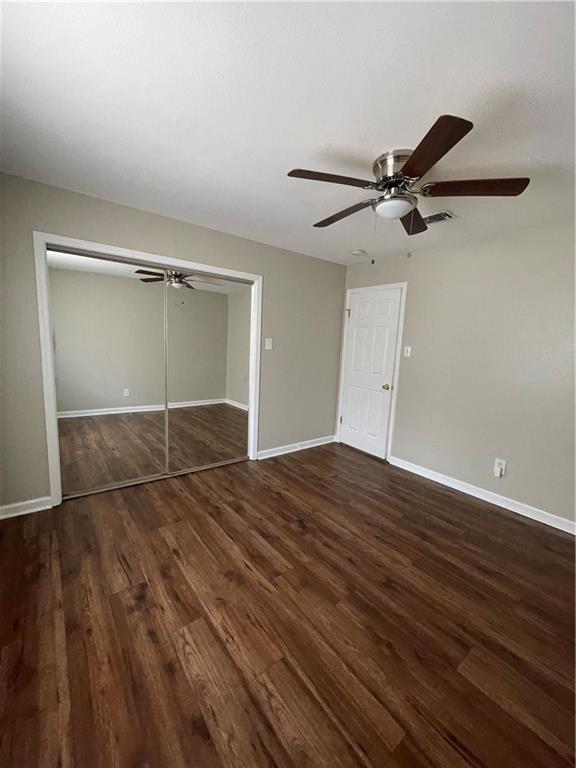 unfurnished bedroom featuring visible vents, a ceiling fan, wood finished floors, a closet, and baseboards