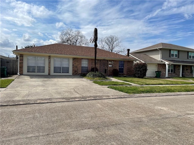 view of front facade featuring brick siding, an attached garage, concrete driveway, and a front lawn