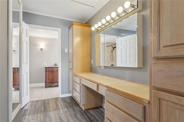 bathroom with vanity, wood finished floors, baseboards, and ornamental molding