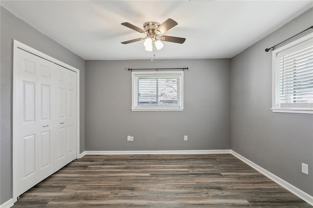 unfurnished bedroom with dark wood finished floors, ceiling fan, baseboards, and a closet