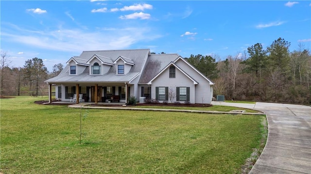 view of front of house with metal roof, central air condition unit, covered porch, and a front yard