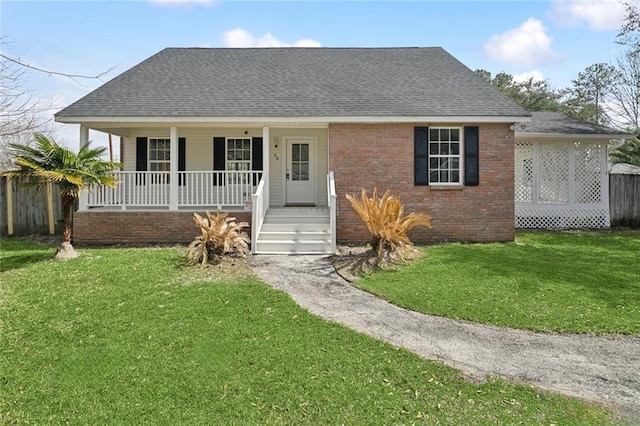 view of front of property with brick siding, a porch, a shingled roof, and a front yard