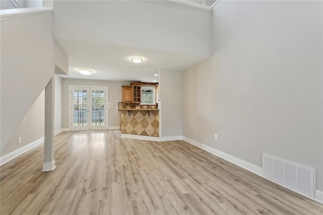 unfurnished living room with visible vents, baseboards, and light wood finished floors