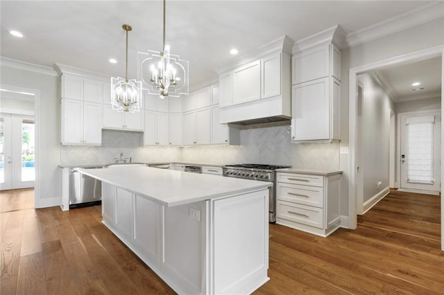 kitchen featuring a kitchen island, dark wood-style floors, appliances with stainless steel finishes, white cabinets, and crown molding