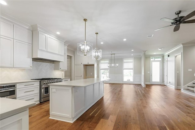 kitchen with stainless steel appliances, light countertops, white cabinetry, crown molding, and backsplash