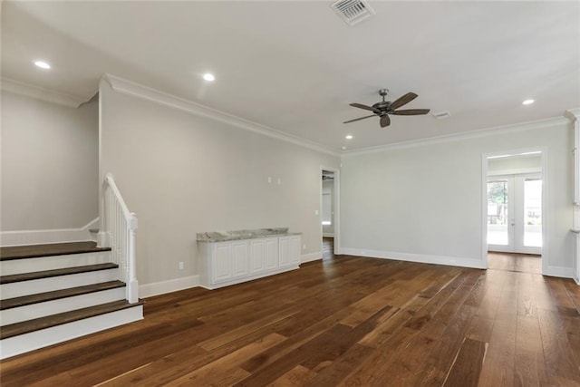 unfurnished living room featuring stairway, dark wood-style floors, visible vents, baseboards, and ornamental molding