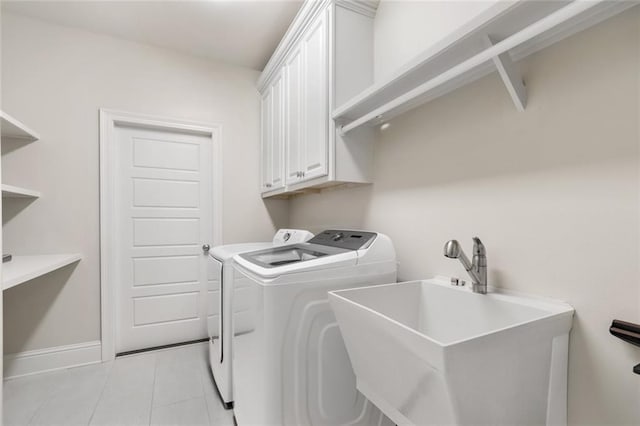 washroom featuring washing machine and clothes dryer, baseboards, light tile patterned floors, cabinet space, and a sink