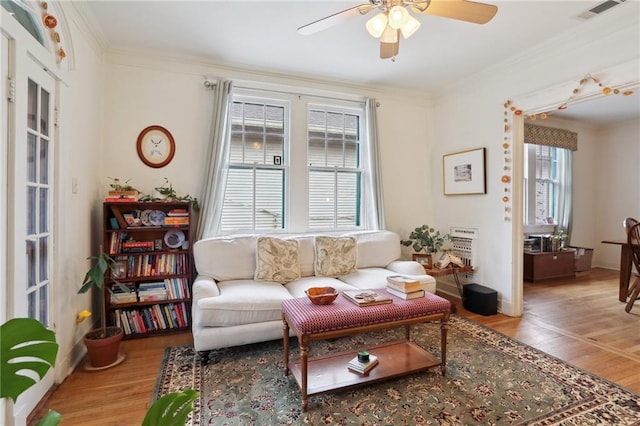 living area with visible vents, wood finished floors, and ornamental molding