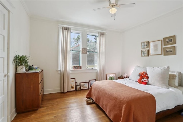 bedroom featuring ornamental molding, ceiling fan, baseboards, and wood finished floors