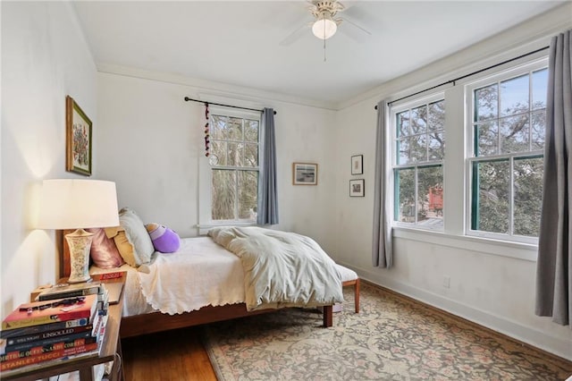 bedroom featuring a ceiling fan, baseboards, and wood finished floors