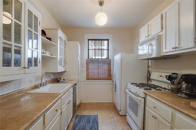 kitchen featuring white appliances, white cabinetry, and a sink