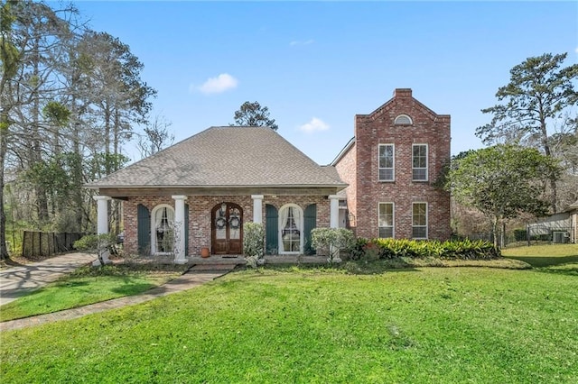 view of front of property with brick siding, roof with shingles, covered porch, and a front lawn