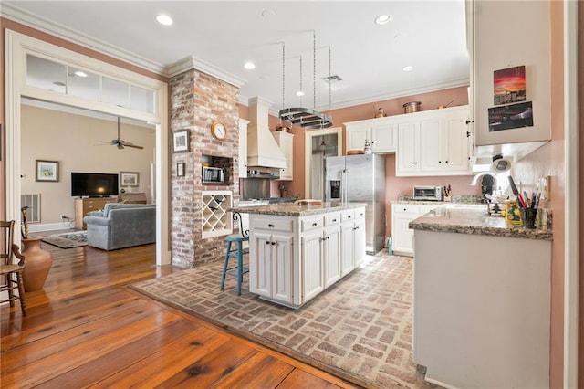 kitchen featuring white cabinets, stainless steel fridge with ice dispenser, premium range hood, and ornamental molding