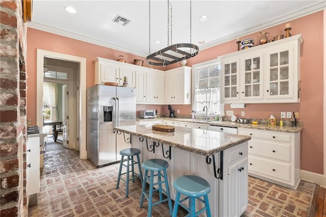 kitchen with visible vents, stainless steel fridge, brick floor, and ornamental molding