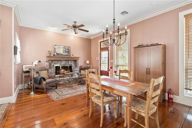 dining space with visible vents, baseboards, ornamental molding, a fireplace, and hardwood / wood-style flooring