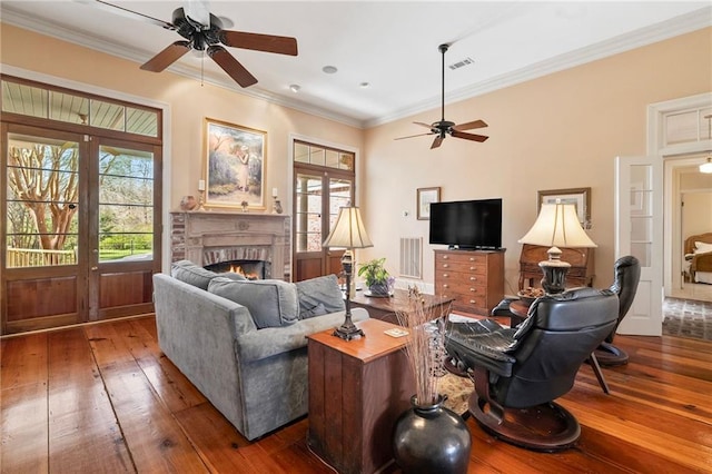 living room with visible vents, hardwood / wood-style floors, french doors, a fireplace, and crown molding