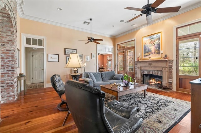 living room with visible vents, a fireplace, crown molding, and hardwood / wood-style floors