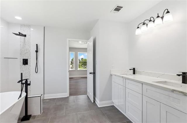 bathroom with tile patterned flooring, visible vents, walk in shower, a freestanding tub, and a sink