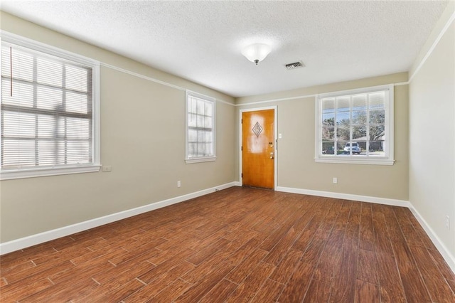 spare room with wood finished floors, visible vents, and baseboards