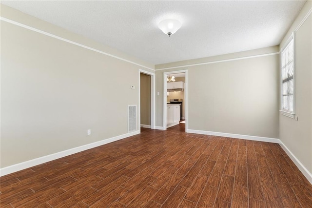 spare room featuring visible vents, a textured ceiling, baseboards, and dark wood-style flooring