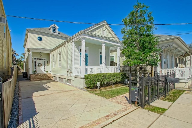 view of front of property featuring a fenced front yard, covered porch, and driveway