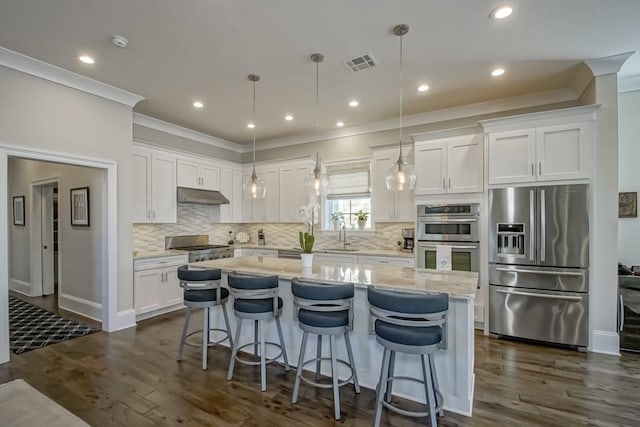 kitchen featuring visible vents, under cabinet range hood, a kitchen island, white cabinetry, and appliances with stainless steel finishes