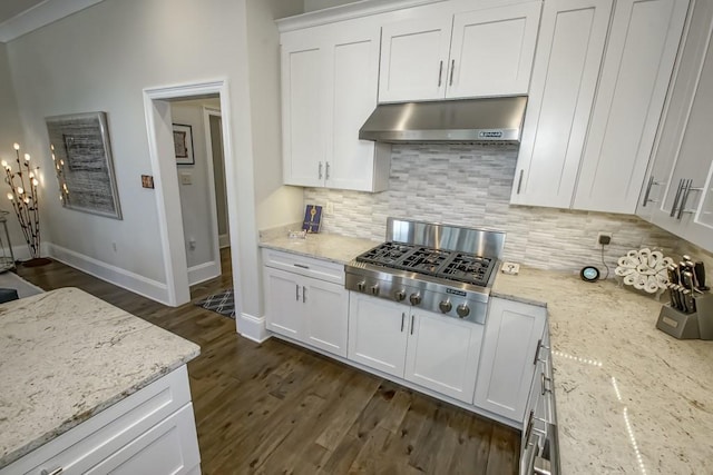 kitchen with tasteful backsplash, under cabinet range hood, stainless steel gas stovetop, dark wood-style floors, and white cabinetry