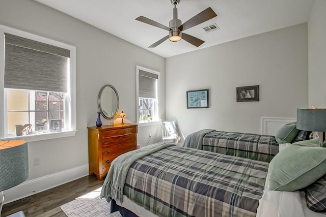 bedroom with ceiling fan, wood finished floors, visible vents, and baseboards