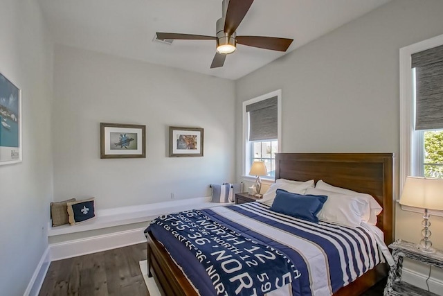 bedroom with ceiling fan, baseboards, multiple windows, and wood finished floors