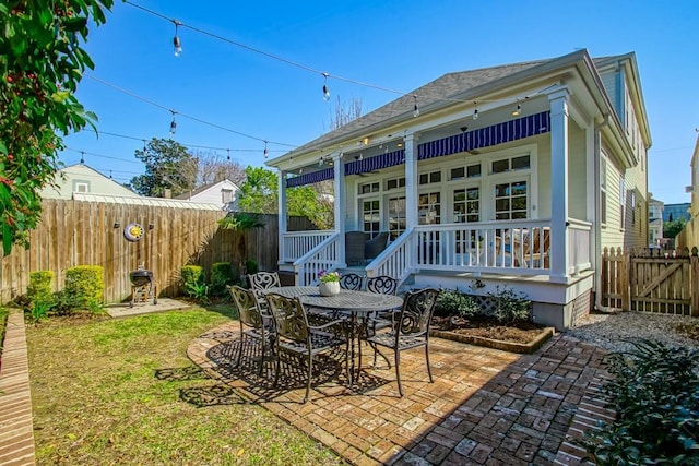 rear view of house featuring a patio area, outdoor dining space, and a fenced backyard