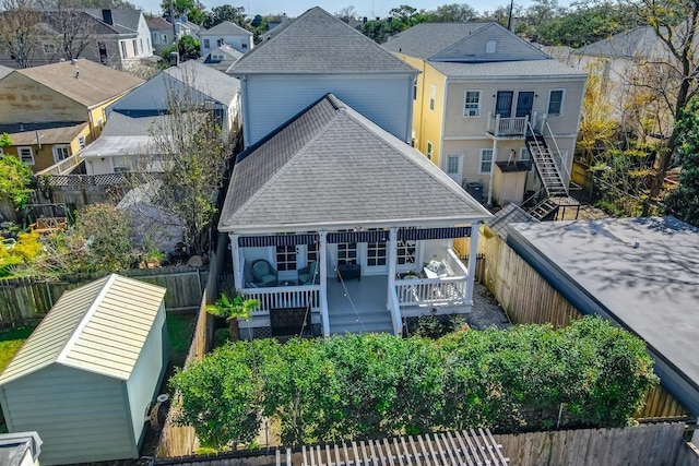 rear view of house featuring a residential view, a shingled roof, and a fenced backyard