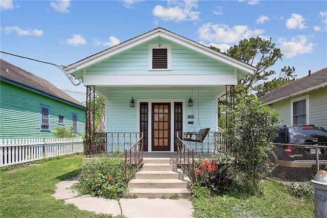 shotgun-style home with a porch and fence