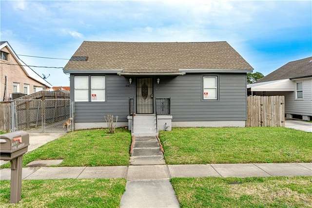 bungalow featuring a front lawn, fence, and roof with shingles