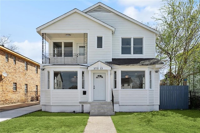 view of front of property featuring a front yard, a balcony, and fence