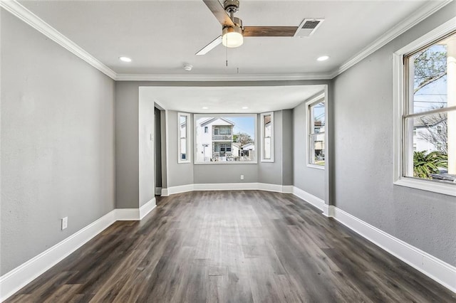 spare room with visible vents, dark wood-type flooring, baseboards, and ornamental molding