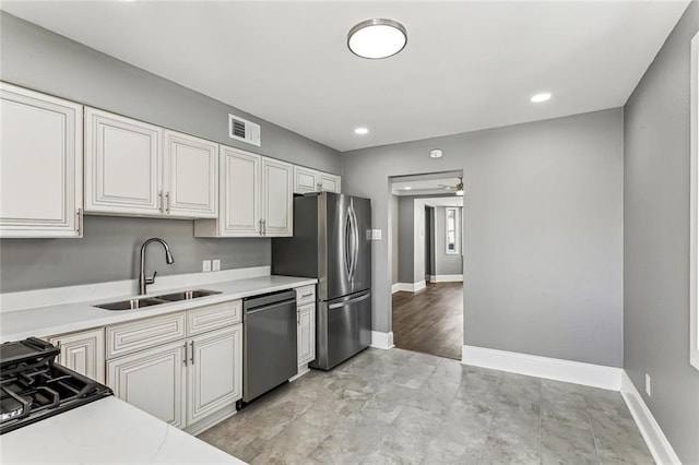 kitchen featuring visible vents, stainless steel appliances, baseboards, and a sink