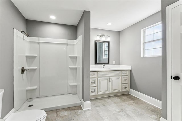 full bath with a shower stall, toilet, vanity, and baseboards