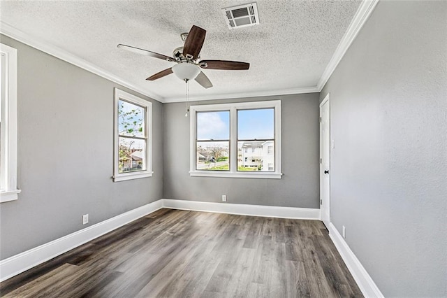 empty room featuring crown molding, wood finished floors, visible vents, and baseboards