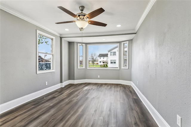 empty room with dark wood finished floors, a textured wall, baseboards, and ornamental molding