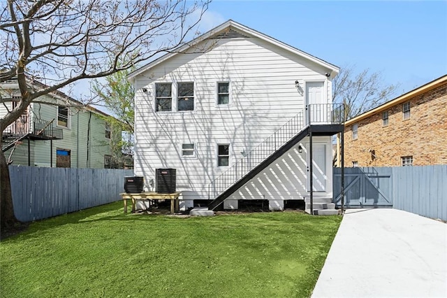 back of property with central AC unit, a lawn, entry steps, and a fenced backyard