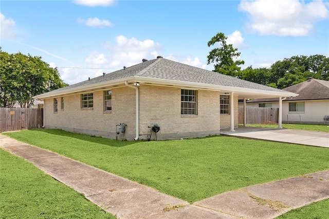 exterior space featuring a lawn, a carport, fence, concrete driveway, and brick siding