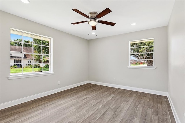 spare room featuring wood finished floors, recessed lighting, a healthy amount of sunlight, and baseboards