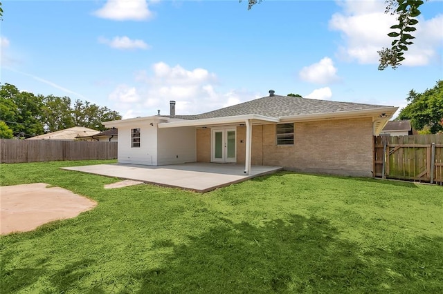 back of property with brick siding, french doors, a fenced backyard, a yard, and a patio