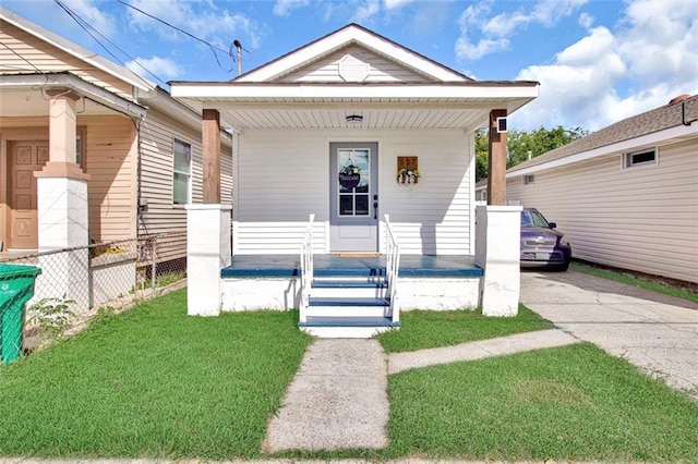 view of front of property featuring a porch, fence, a front yard, and aphalt driveway