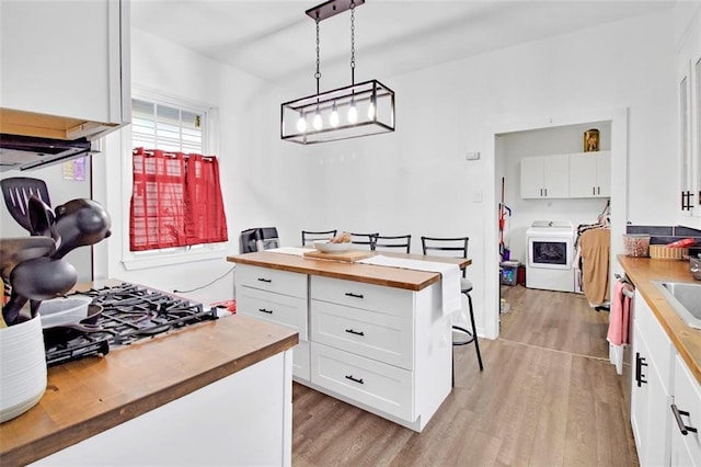 kitchen with light wood finished floors, wooden counters, pendant lighting, white cabinets, and washer / clothes dryer