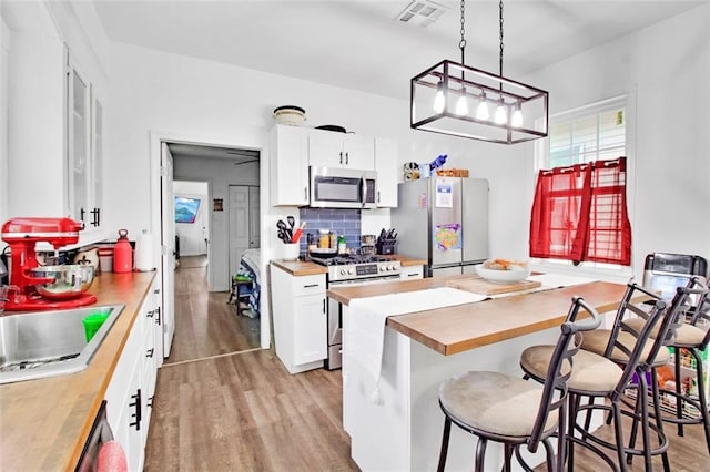 kitchen with visible vents, a sink, stainless steel appliances, light wood-type flooring, and butcher block counters