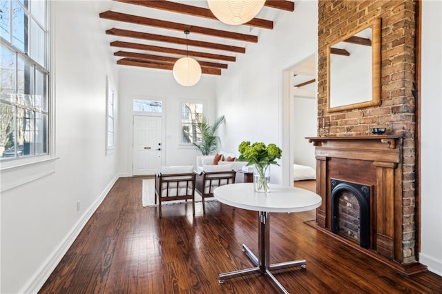 foyer featuring beam ceiling, a fireplace, baseboards, and hardwood / wood-style flooring